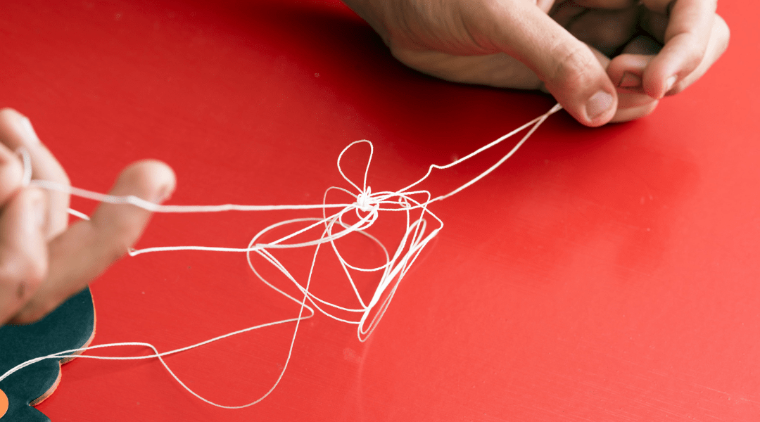 red background with a person trying to unravel a tangled white string.